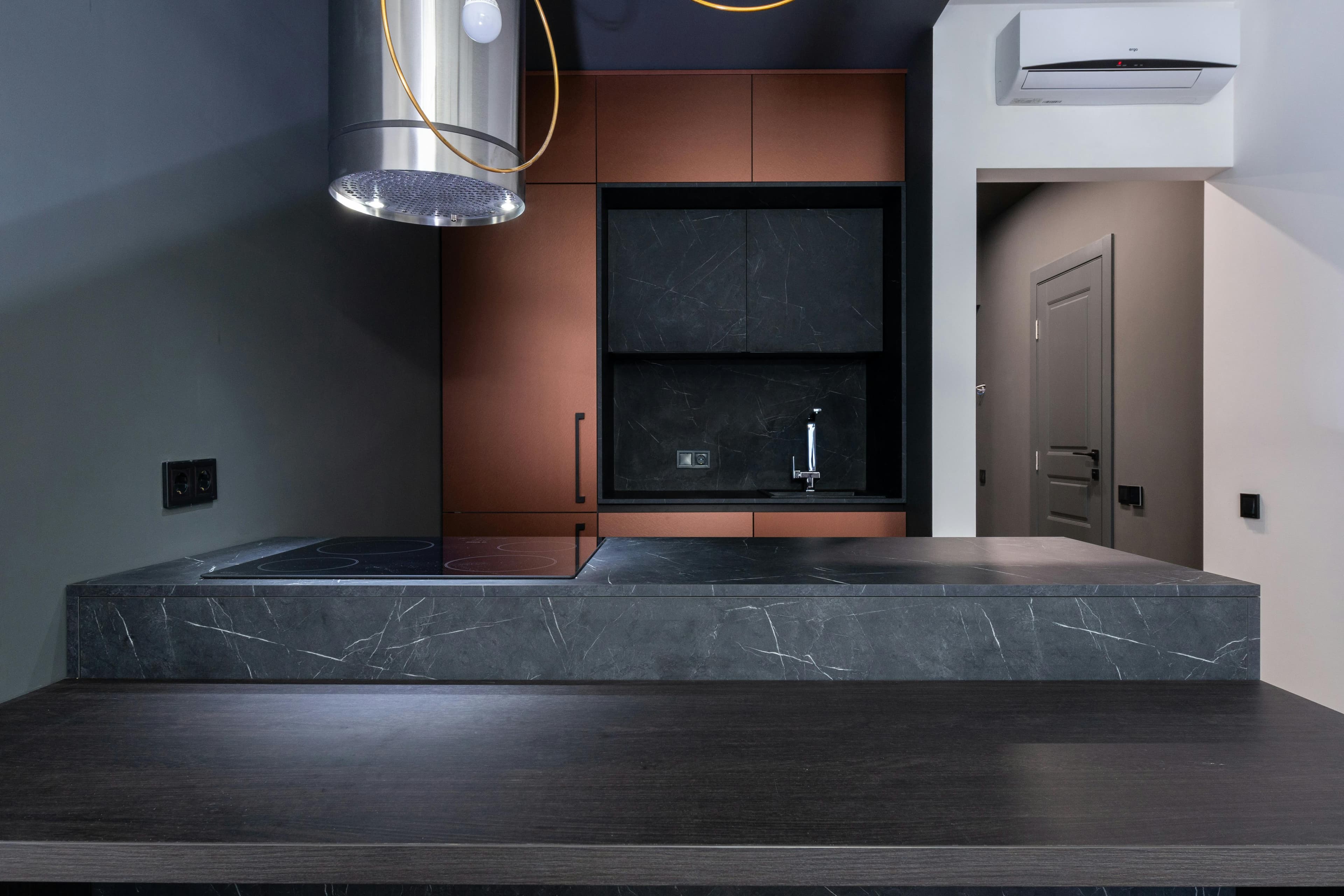 Dark gray quartzite countertop with dramatic veining and copper cabinets
