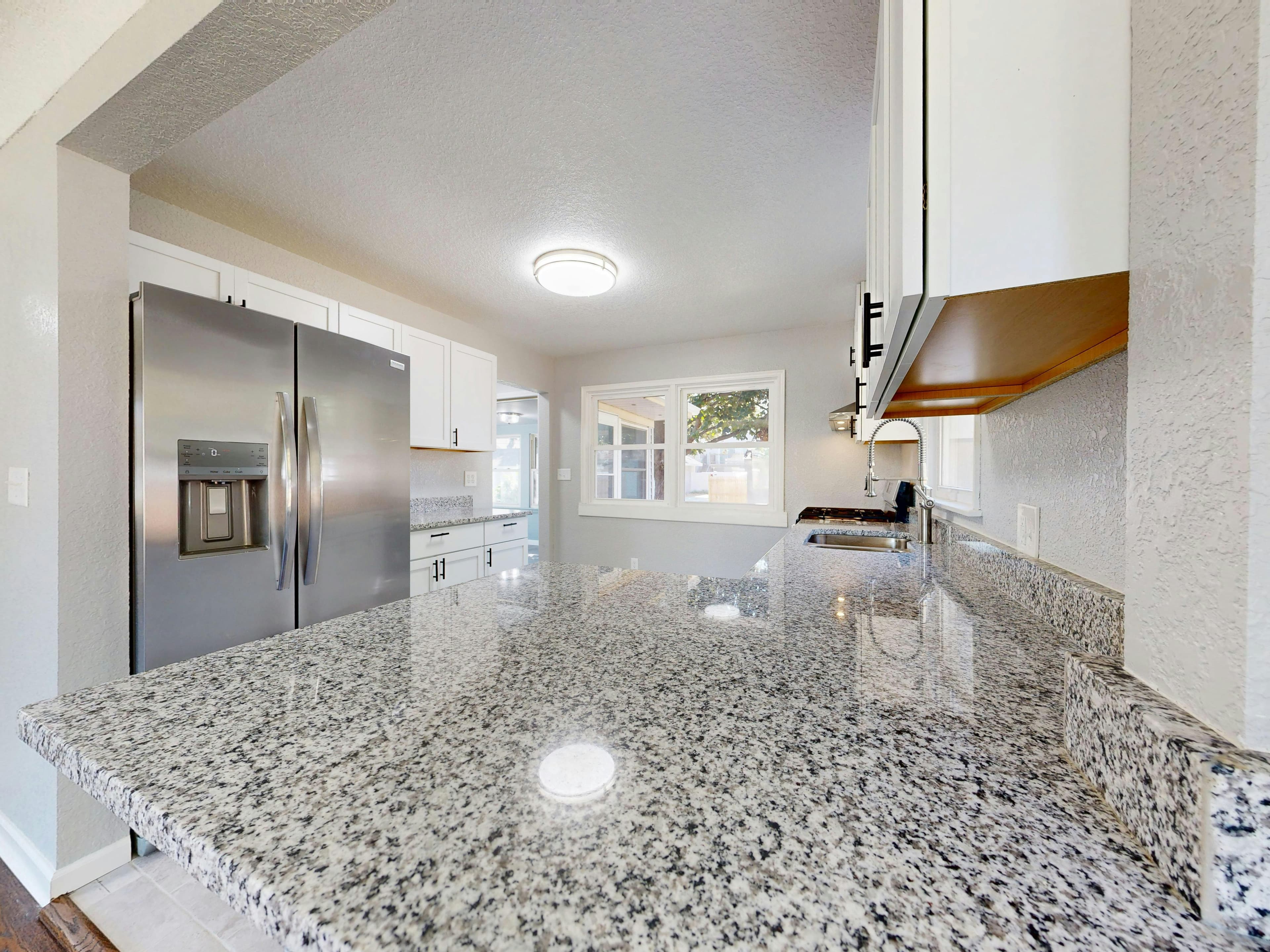 Natural granite countertop with white cabinets in a modern kitchen